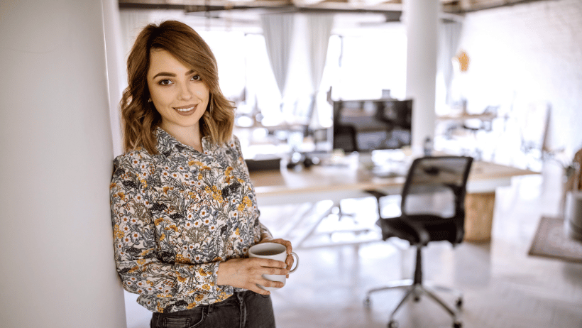 Blog20Covers20-202023-04-04T142835.021 Confident business woman wearing a floral shirt and holding a cup of tea in an office setting