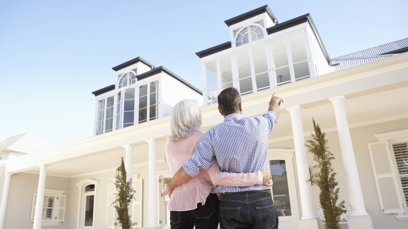Older couple standing outside their home while pointing at a window