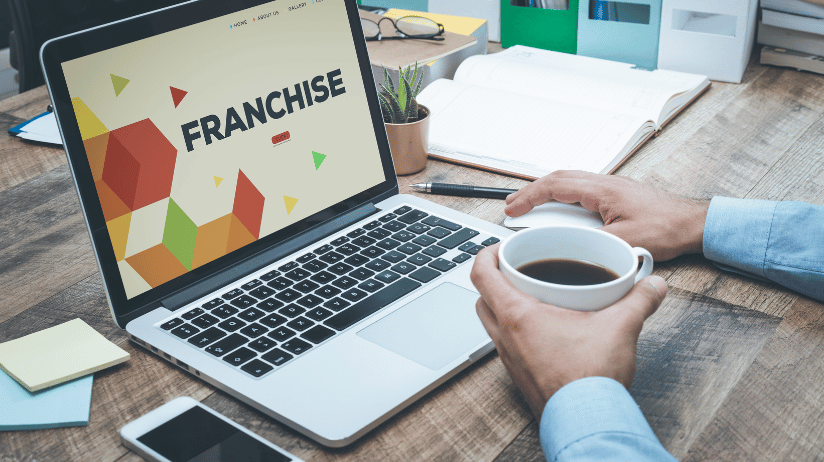Blog20Covers20-202023-08-02T101940.745 Businessman holding a cup of coffee while reviewing a franchise presentation on a laptop