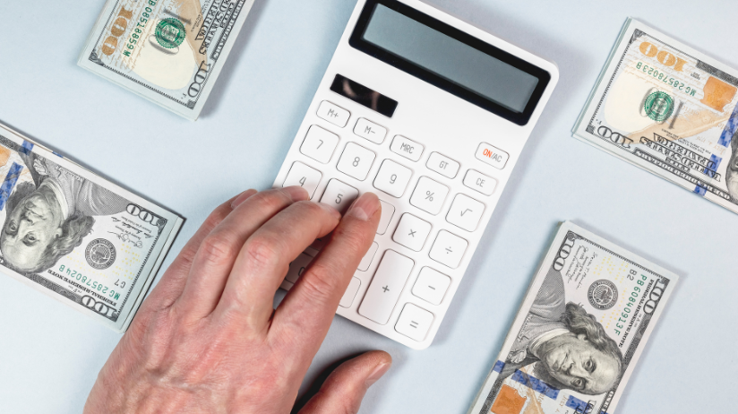 Money on a desk and a hand on a calculator