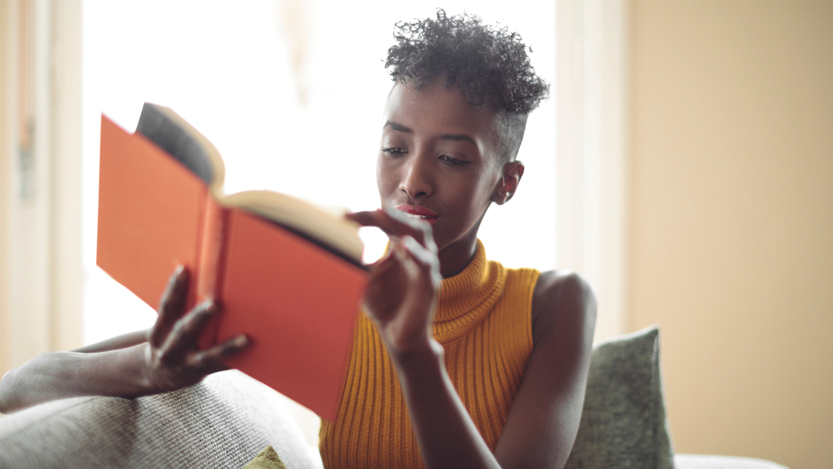 Blog20Covers20285729 Young Black woman reading an orange book on a couch