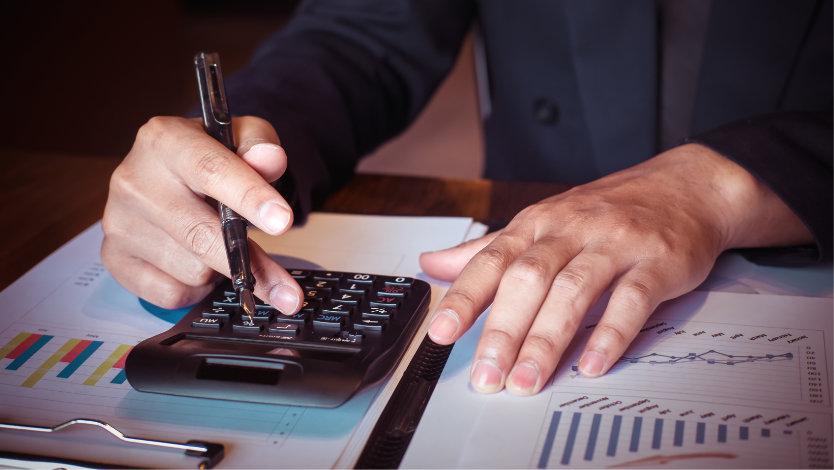 Blog20Covers20286229 Businessperson at a desk with a calculator and business analytics