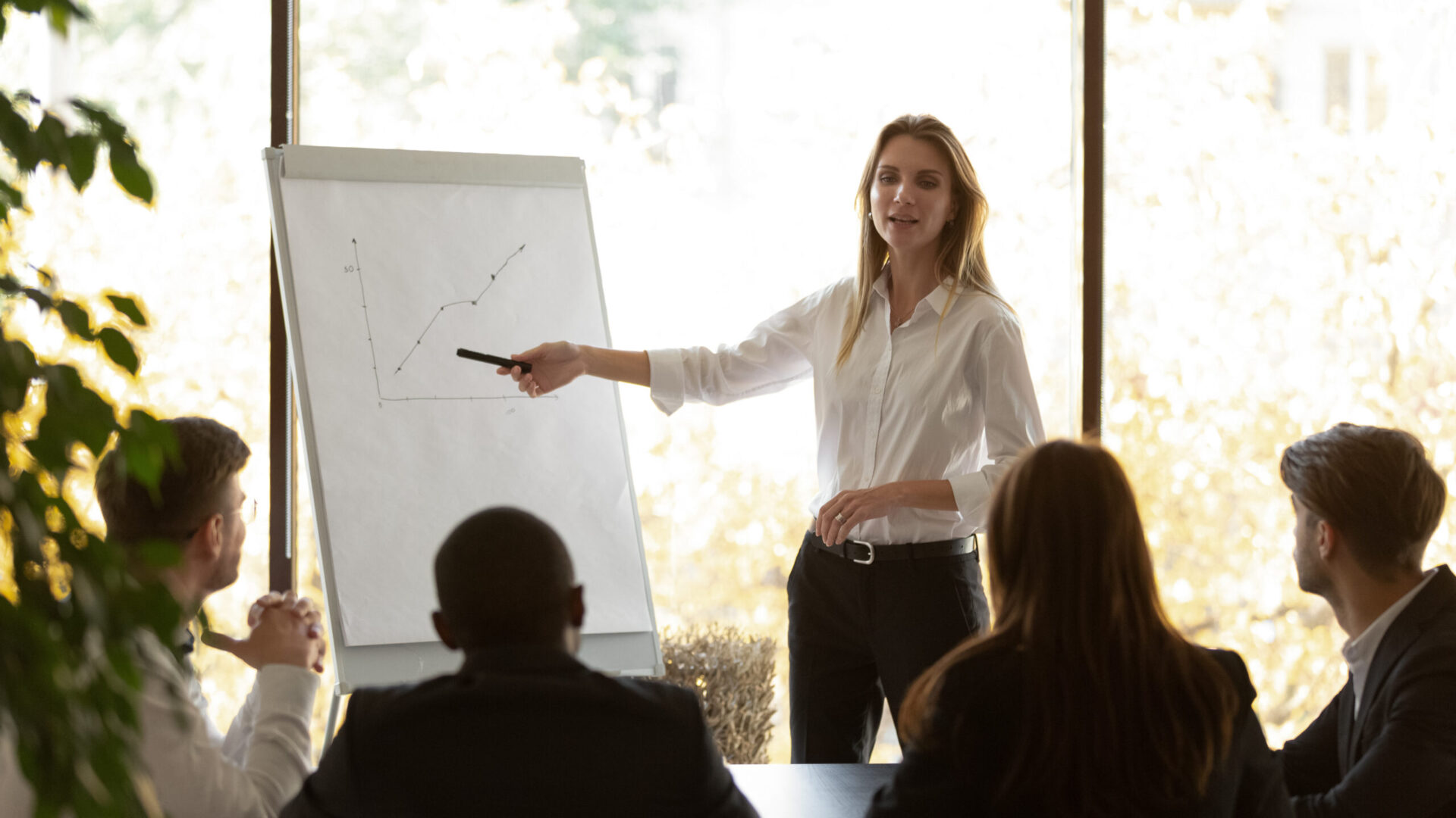 Female speaker give flip chart presentation at conference training meeting Female business coach speaker pointing on flip chart presenting work results graph at conference office meeting