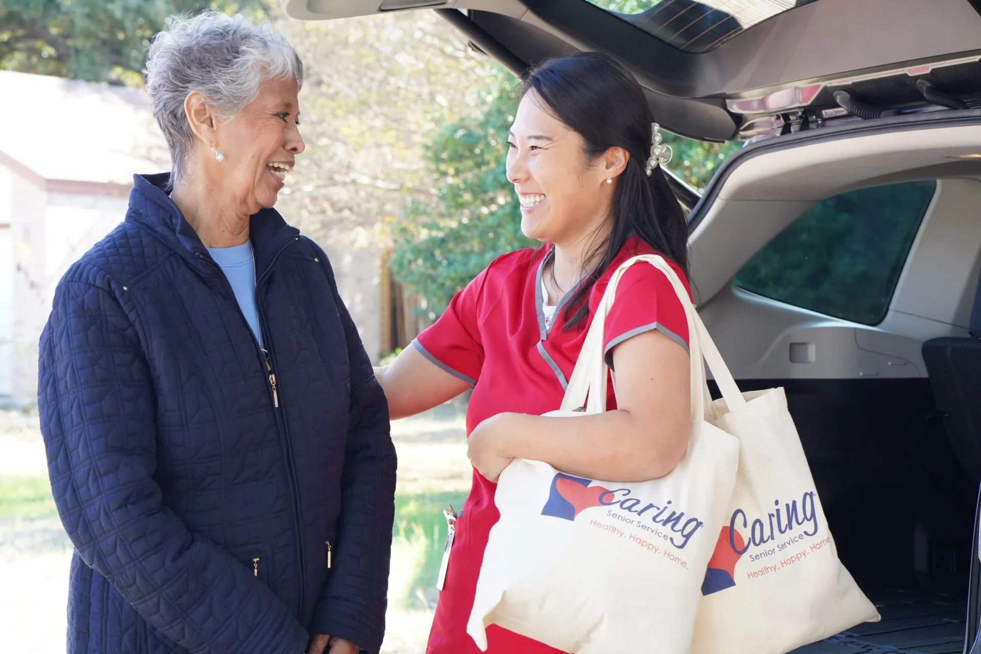 Caregiver smiling while carrying a senior's grocery bags