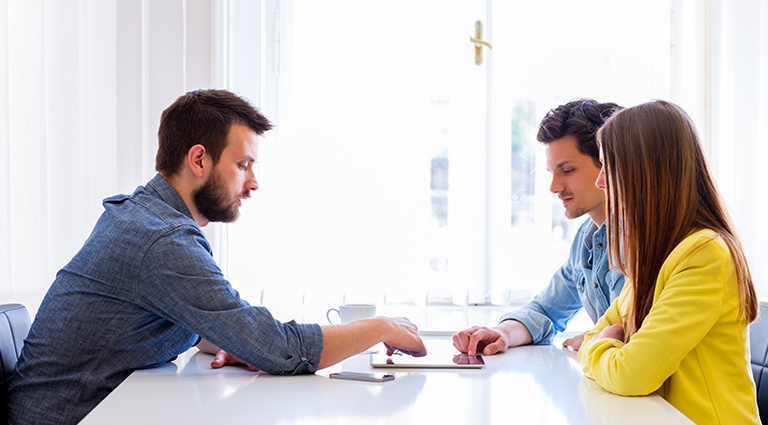 Young couple discussing a business deal witting at a white table