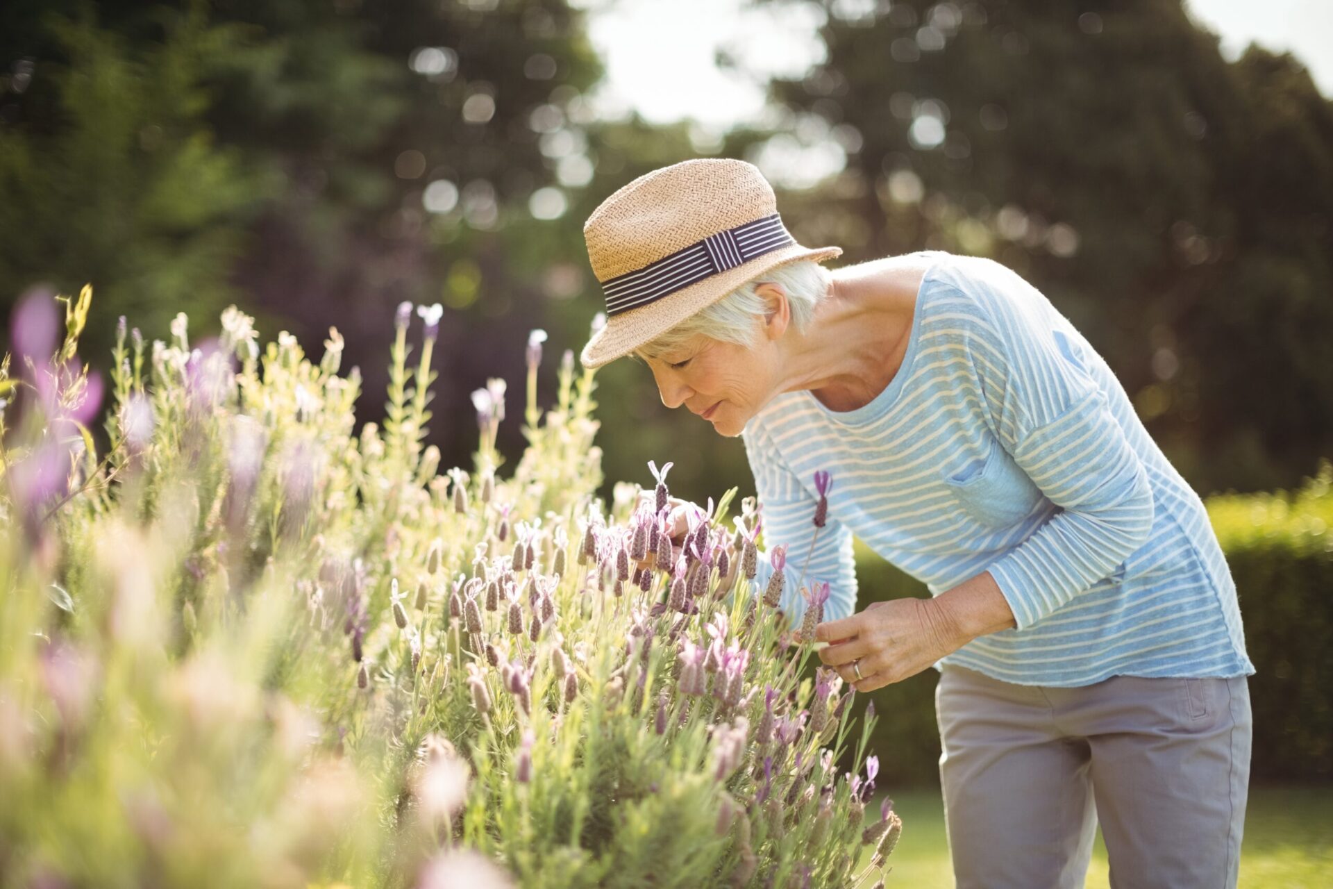 Senior woman smelling purple flowers outdoors
