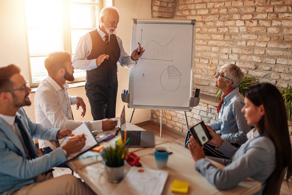 .Businessman making a presentation in office Older businessman presenting to a group of co-workers