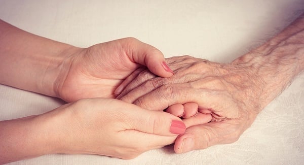 Female caregiver holding a senior's hand