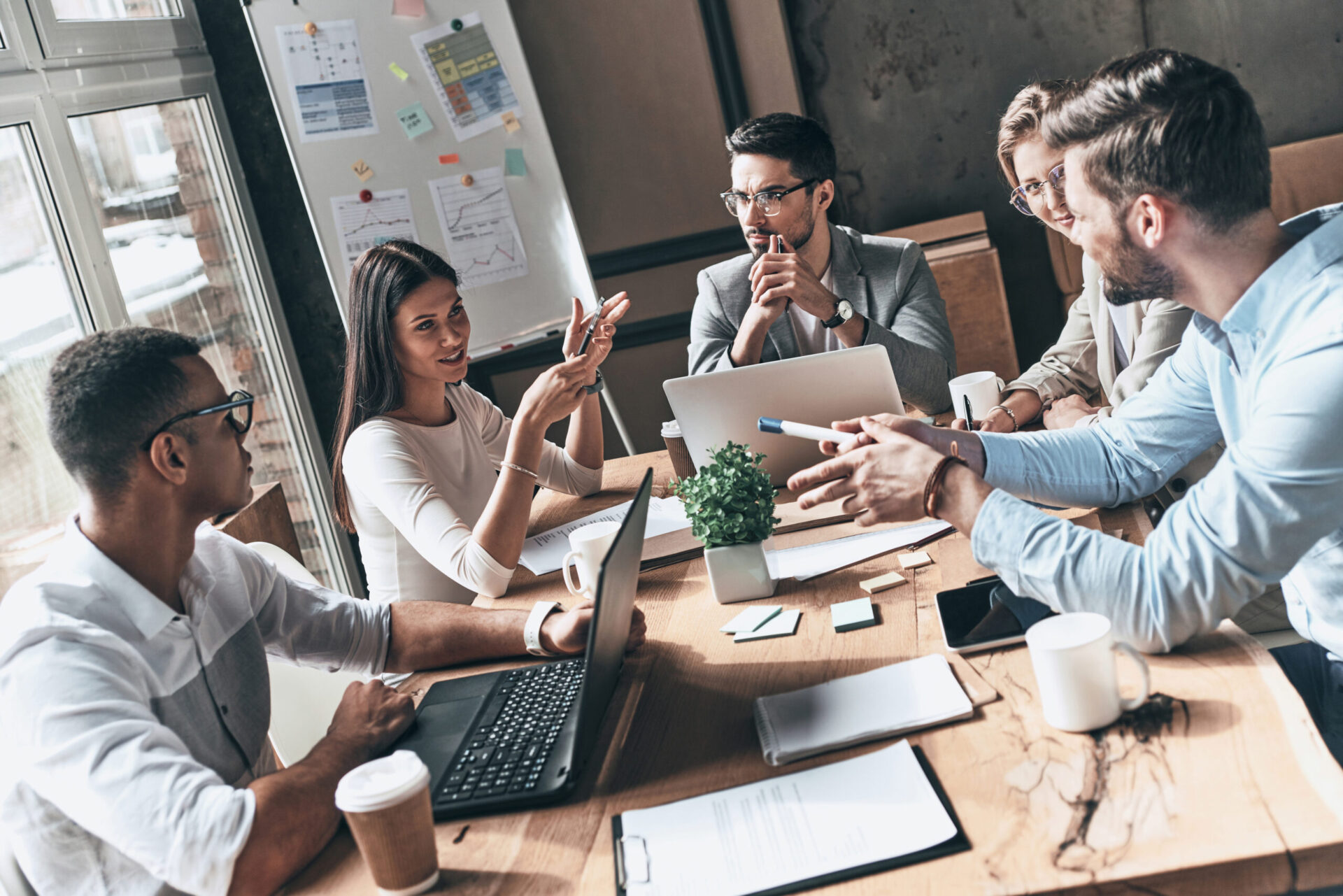 Top view of young modern people in smart casual wear discussing business while working in the creative office